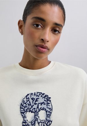 Cremfarbener Sweatshirt mit einem blauen Totenkopf-Graphic und Text. Weiches Material, runder Ausschnitt und gerippte Bündchen. Einfaches, lässiges Design.