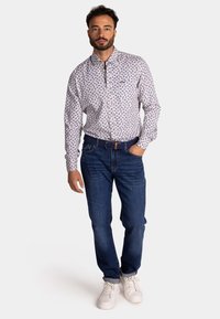 Witte overhemd met blauwe bladerenpatroon, gecombineerd met donkerblauwe jeans en witte sneakers. Heeft een klassieke pasvorm en kraagontwerp.