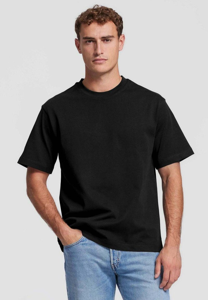 Zwarte katoenen t-shirt met een ronde halslijn en korte mouwen, met een relaxte pasvorm en een soepele textuur, gecombineerd met blauwe jeans.