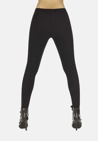 Dolna część tułowia ubrana w czarne legginsy i czarne, sznurowane, wysokie botki na obcasie, stojąca z nogami rozstawionymi na białym tle.