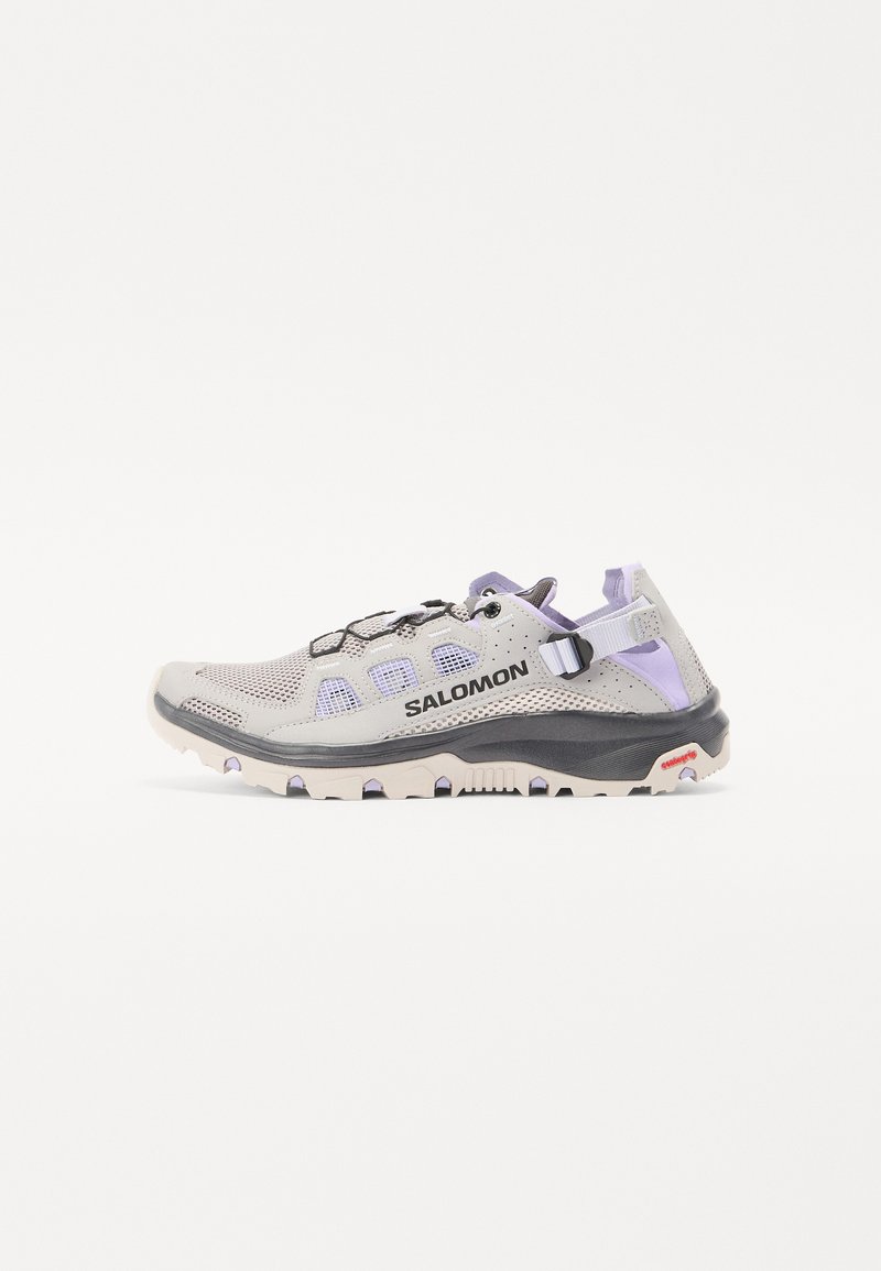 Hellgrauer Sportschuh mit lila Akzenten, Mesh-Obermaterial, Gummisohle und Schnürsystem. Verfügt über eine verstärkte Zehen- und Fersenpartie für Haltbarkeit.