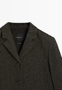 Veste gris foncé à motif chevrons avec revers crantés et deux boutons noirs, étiquette Massimo Dutti, fabriquée en Roumanie.