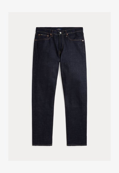 Sötét indigó egyenes szárú farmer ötlábbal, gombos és cipzáras záródással, kontrasztos narancssárga varrással egyszínű háttéren.