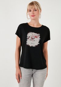Zwarte katoenen t-shirt met een ronde halslijn, korte mouwen en een bloemenafbeelding in rood en wit op de voorkant.