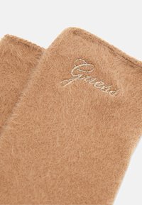 Polsini marroni e pelosi con una texture morbida, caratterizzati da una "G" ricamata in argento su un lato. I bordi sono rifiniti con una cucitura pulita.