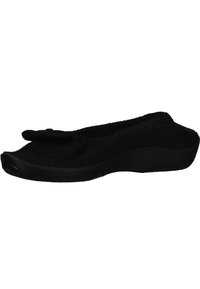 Scarpa nera in maglia slip-on con punta rotonda, suola piatta e un delicato dettaglio a fiocco nella parte anteriore. Texture morbida e design flessibile per il massimo comfort.