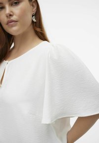 Witte getextureerde blouse met korte, opbollende mouwen en een keyhole-halslijn. Voorzien van een gladde stof en een subtiel kreukelpatroon.