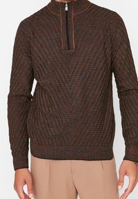 Strick-Sweatshirt mit Reißverschluss in Braun mit strukturiertem Muster und kontrastierenden orangen und blauen Sprenkeln; verfügt über einen hohen Kragen sowie gerippte Bündchen und Saum.