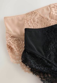 Beige and black lace-trimmed women's underwear laid overlapping on a light surface showing floral lace details.
