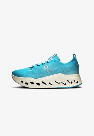 Light blue athletic shoe with a textured mesh upper, white sole featuring cutouts, and contrasting dark laces. Rounded toe and padded collar.