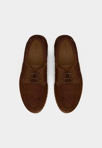 Καφέ καστόρινα casual παπούτσια με κορδόνια, ορατά ράμματα, επίπεδη σόλα και ετικέτα μάρκας "Pier One" στο εσωτερικό κάθε παπουτσιού.