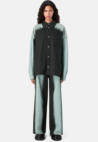 Přesně střižená košile s dlouhým rukávem v černozeleném gradientu se zámečnickou kapsou na prsou. V setu s kalhotami s širokými nohavicemi, obě vyrobené z jemné, lesklé tkaniny.