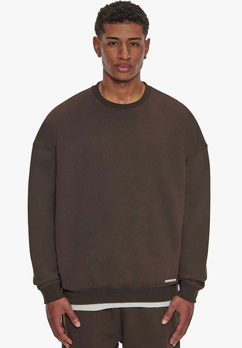 Dunkelbrauner Sweatshirt mit Rundhalsausschnitt, überschnittenen Schultern, gerippten Bündchen und weicher Textur. Verfügt über ein kleines Etikett am Saum.