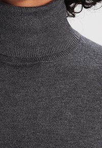 Dunkelgrauer Rollkragenpullover mit einer gerippten Textur am Kragen und am Körper, der eine figurbetonte Passform und ein weiches Strickmaterial aufweist.