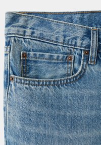 Gros plan de la poche avant d’un jean en denim bleu avec des rivets en cuivre, des coutures visibles et une texture de tissu délavé.