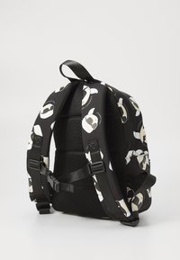 Black backpack with a lightweight and textured design, featuring a repeating cartoon face pattern. Adjustable straps and a mesh back panel.