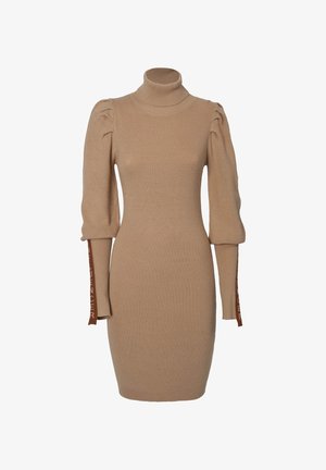 Robe en tricot beige avec col roulé, manches bouffantes et coupe ajustée. Les manches présentent des inscriptions brunes le long des bords.