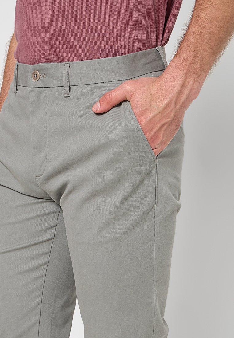 Hellgraue Hosen mit glatter Textur, seitlichen Taschen und Knopfverschluss. Minimalistisches Design, taillierte Passform und keine sichtbaren Muster.