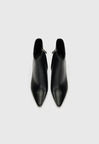 Bottines en cuir noir à bout pointu, surface texturée, zips latéraux et design élégant, présentées en vue de dessus.