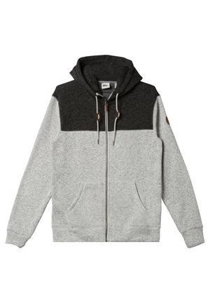 Sudadera con cremallera gris que tiene una sección superior gris oscuro, bolsillos frontales, cordones ajustables y una tela suave y texturizada. Los acentos incluyen herrajes en color marrón.