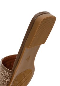 Sandale à talon haut beige avec un dessus en cuir texturé et une semelle en caoutchouc lisse. La semelle présente des rainures pour l'adhérence et a une forme de bout arrondi.