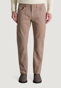 Pantalones de color marrón claro con una textura suave, que presentan bolsillos delanteros y detalles de costura sutiles, combinados con botas de tobillo grises.