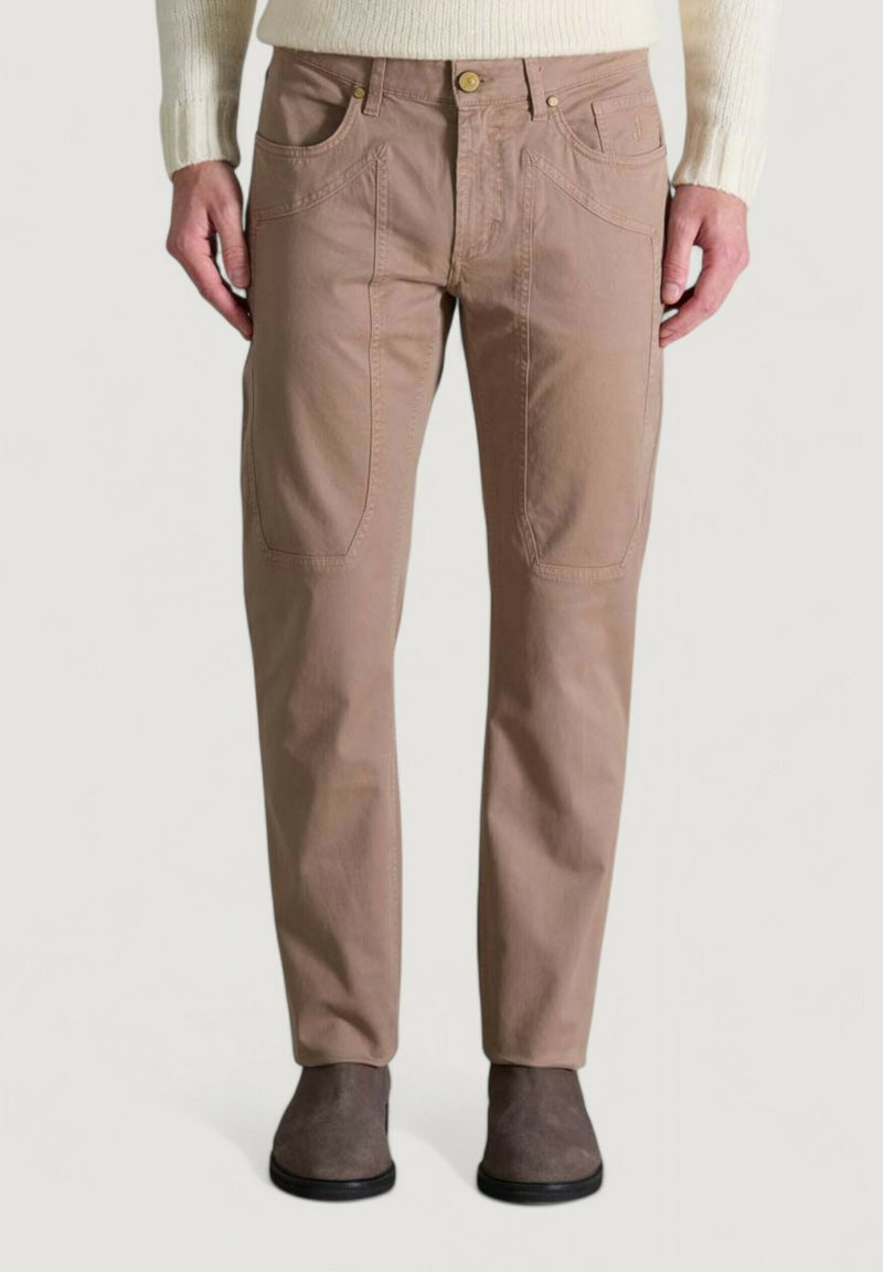 Pantalones de color marrón claro con una textura suave, que presentan bolsillos delanteros y detalles de costura sutiles, combinados con botas de tobillo grises.