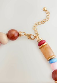 Perlenkette mit verschiedenen Formen und Farben: rote, pinke, blaue und bernsteinfarbene Perlen mit einem Verschluss und Kettenakzenten in Goldfarbe.