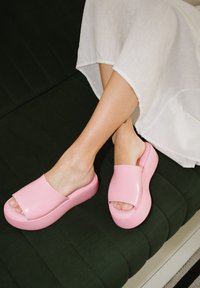Sandali piattaforma rosa con design open toe, realizzati in materiale lucido, dotati di una larga cintura superiore e di una suola spessa.