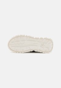 Suola in gomma bianca per sneakers con motivi e scanalature testurizzati. Presenta un'impronta del logo discreta e accenti scuri a contrasto sul tallone.