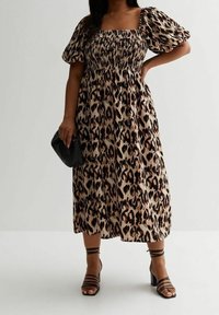 Leopardenmuster Midi-Kleid mit quadratischem Ausschnitt und smockiertem Oberteil, mit Puffärmeln. Kombiniert mit schwarzen Riemchensandalen und einer Clutch.
