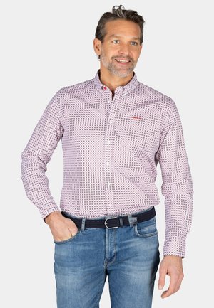 Overhemd met knopen in een roze en witte geometrische print, lange mouwen en een kraag; gecombineerd met blauwe denim jeans en een donkere riem.