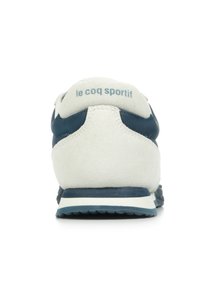 Baskets blanches et marines avec une tige en daim et synthétique, un col rembourré, une semelle plate et le logo "le coq sportif" sur le talon.