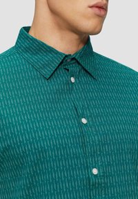 Teal overhemd met knopen en een kraag, met een gestructureerd patroon van witte verticale lijnen en witte knopen.