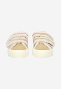 Tan slip-on kengät, joissa on paksuja, pehmeitä, kremervärisiä karvareunuksia. Pyöreä siluetti, jossa on teksturoitu päällinen ja vaaleat pohjat.