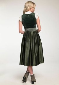 Green velvet bodice with ruffled white collar, pleated dark green skirt featuring a subtle pattern, and gray ankle boots with lace trim.