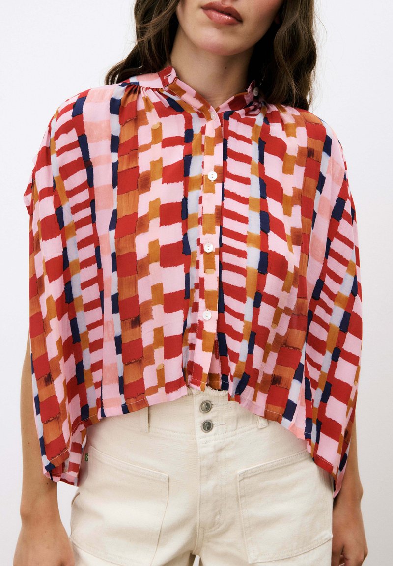 Bunte Kurzarmbluse mit einem abstrakten Muster in Pink, Rot und Marineblau, mit Kragen und Knopfverschluss. Leichter, transparenter Stoff.
