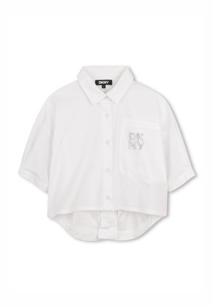 Chemisier blanc raccourci avec col rabattable, manches courtes, fermeture à boutons sur le devant et une poche ornée d'un logo DKNY en strass.