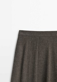 Jupe en laine marron avec une ceinture ajustée et des plis doux, montrée de la taille jusqu'au milieu de la cuisse sur fond blanc.