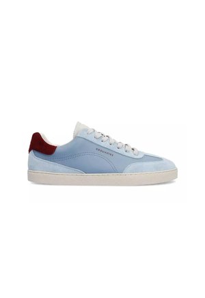 Sneaker bassa azzurro chiaro con lacci bianchi, suola beige, dettagli in camoscio e toppa sul tallone rosso scuro, con etichetta "GROUNDIES" sul lato.