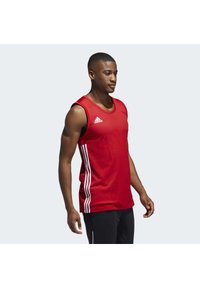 Débardeur de sport rouge avec un col rond, présentant des accents en trois rayures blanches de chaque côté et le logo Adidas sur la poitrine.