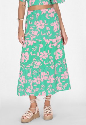 Gonna maxi in tessuto verde con stampa floreale rosa, design a strati e vita elasticizzata. Indossata con sandali espadrilles beige.