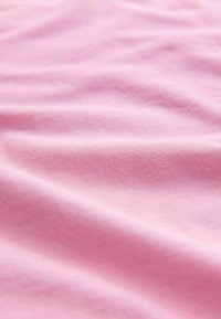 Material de bumbac roz deschis cu textură netedă, prezentând falduri și cute blânde, evidențiind moliciunea și maleabilitatea materialului.