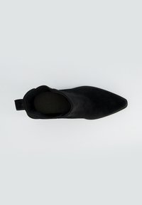 Botín negro, material de ante, diseño de punta afilada, textura suave, tirador en el talón, estilo minimalista, acolchado oscuro interior visible.