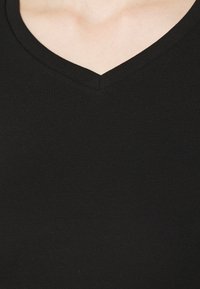 Sort v-hals t-shirt lavet af blødt stof. Har en ribbet halsudskæring og et tætsiddende design, der viser minimale sømme og en ensartet tekstur.