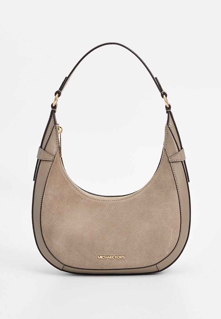 Beige suède handtas met een gebogen vorm, een donkere schouderband en gouden hardware. Voorzien van een ritsluiting en een reliëflogo aan de voorkant.