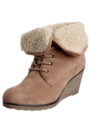 Tanfarbene Keilabsatz-Stiefelette aus Wildleder mit Schnürung vorne und umgeschlagener, cremefarbener Lammfellmanschette.