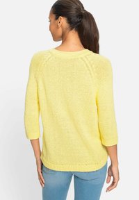 Gelbes Strickpullover mit Dreiviertelärmel, gerippten Bündchen und einer lockeren Passform. Weiche Textur und offenes Strickmuster.