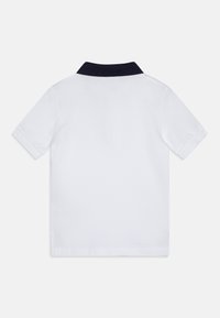 Klassisk hvid polo skjorte med en marineblå krave, korte ærmer og et struktureret stof. Enkel design uden frontdetaljer.