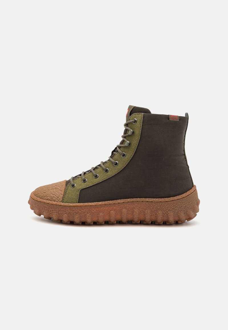 Botte montante avec semelle texturée marron, zone de laçage vert olive et dessus en matériau marron foncé, vue de côté sur fond blanc.